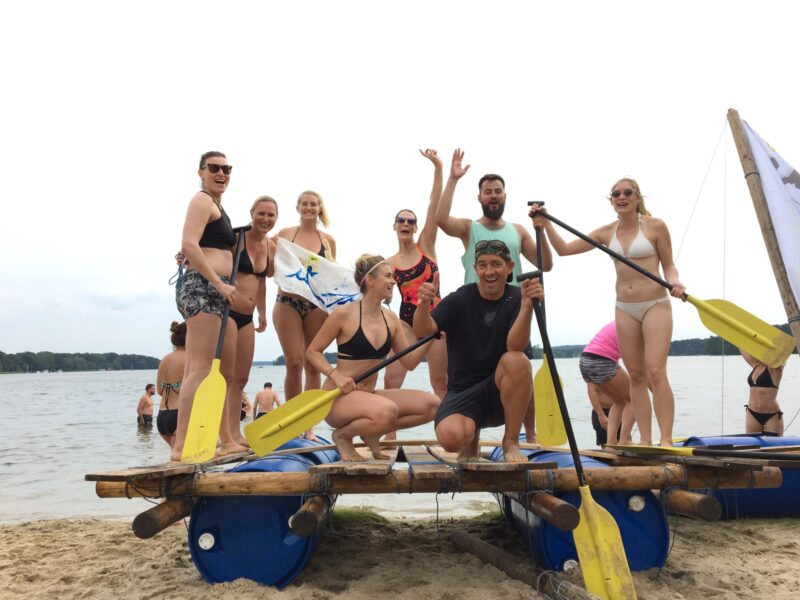 Zurück am Strand feiert ein Team die erfolgreiche Jungfernfahrt des selbstgebauten Floß.